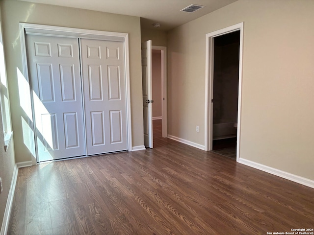 unfurnished bedroom featuring dark hardwood / wood-style floors and a closet