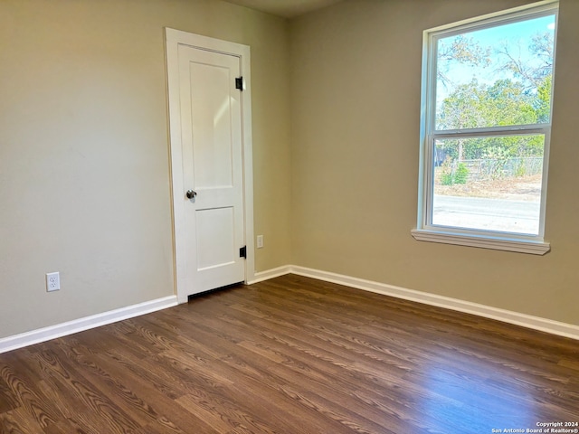 empty room featuring a wealth of natural light and dark hardwood / wood-style flooring