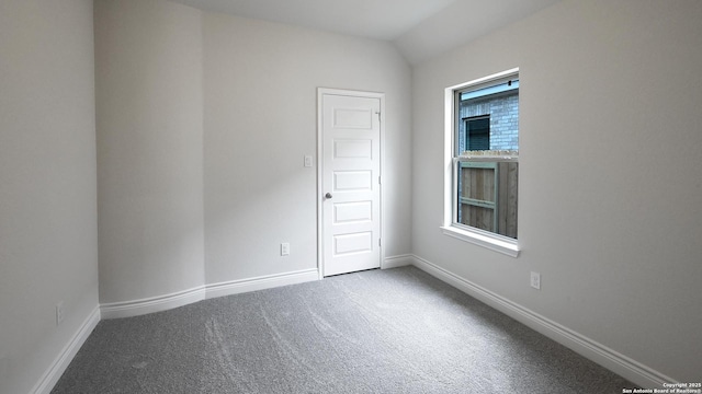 carpeted spare room featuring vaulted ceiling