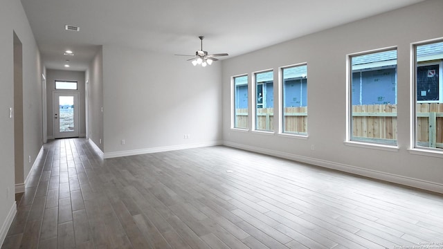 unfurnished room featuring hardwood / wood-style floors, a wealth of natural light, and ceiling fan