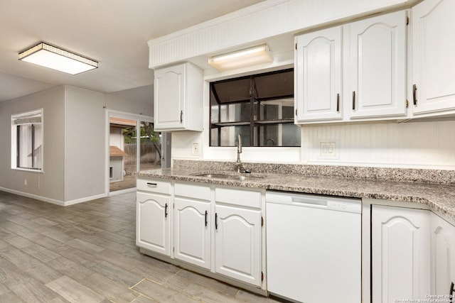 kitchen featuring white dishwasher, sink, and white cabinetry