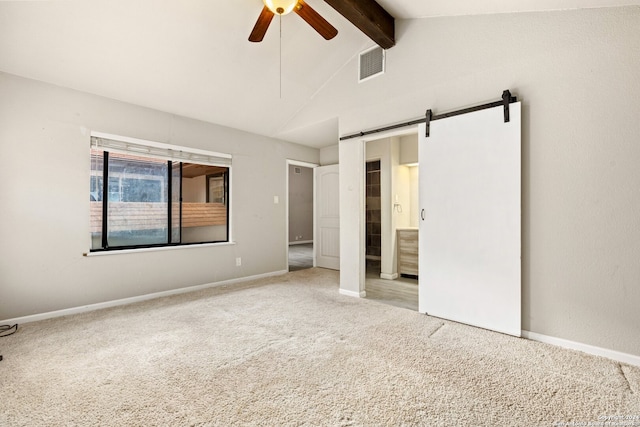 unfurnished bedroom featuring light carpet, a barn door, lofted ceiling with beams, ensuite bathroom, and ceiling fan