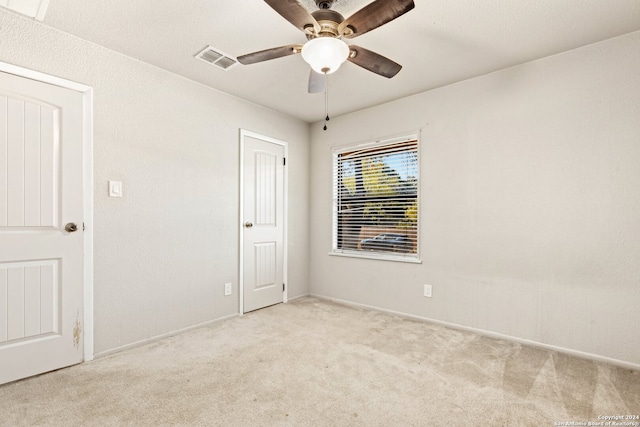 empty room featuring ceiling fan and light colored carpet