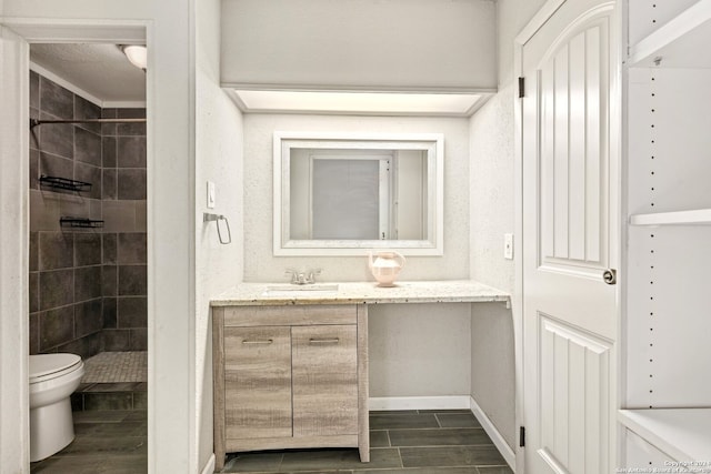 bathroom with vanity, tiled shower, and toilet