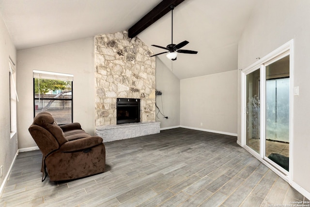 living room with beam ceiling, ceiling fan, high vaulted ceiling, wood-type flooring, and a stone fireplace