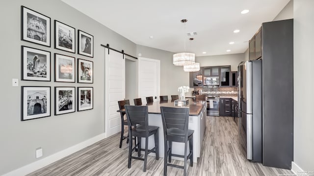 dining area featuring a barn door, light wood-type flooring, and an inviting chandelier