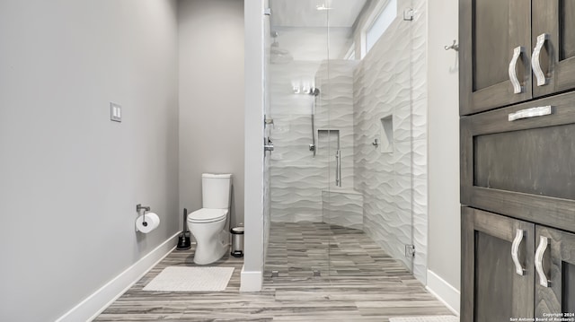 bathroom featuring a shower with door, toilet, and wood-type flooring