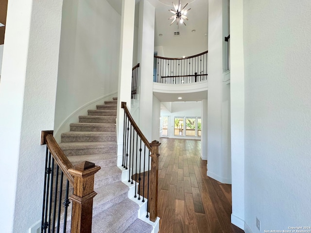 stairs featuring a chandelier, hardwood / wood-style flooring, and a towering ceiling