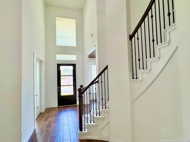 entrance foyer with hardwood / wood-style flooring and a towering ceiling