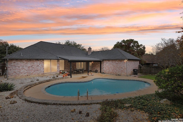 pool at dusk featuring a patio