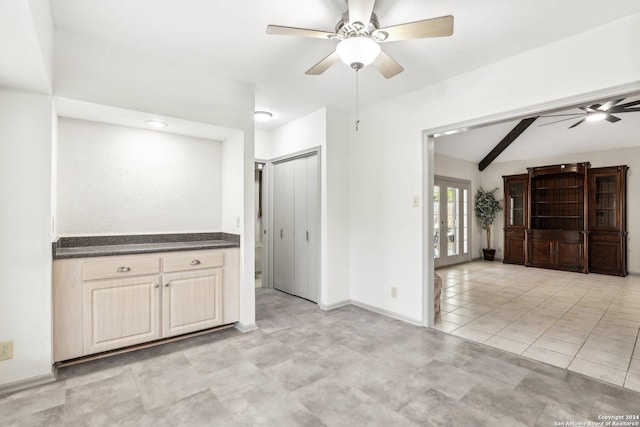 tiled empty room featuring ceiling fan, lofted ceiling with beams, and french doors