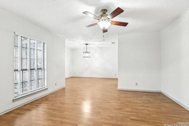 unfurnished room with a textured ceiling, light hardwood / wood-style floors, and ceiling fan