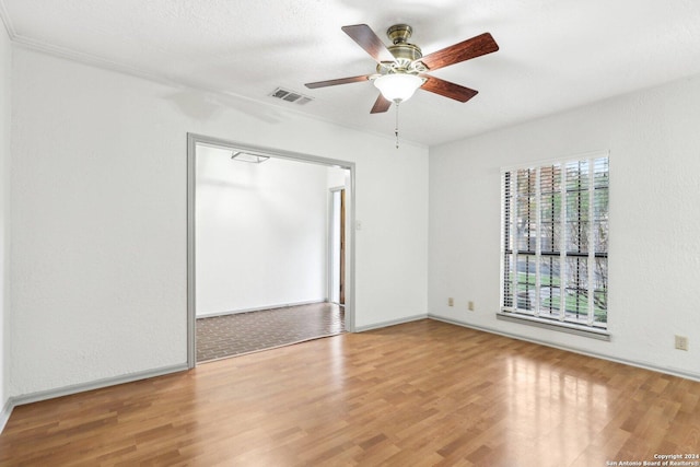 empty room featuring a textured ceiling, hardwood / wood-style flooring, ceiling fan, and ornamental molding