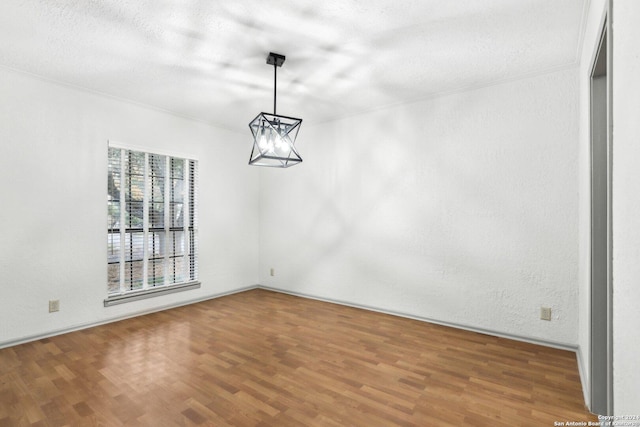 unfurnished dining area featuring wood-type flooring, a textured ceiling, and an inviting chandelier