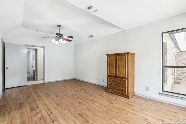 empty room with a textured ceiling, vaulted ceiling, light hardwood / wood-style flooring, and ceiling fan