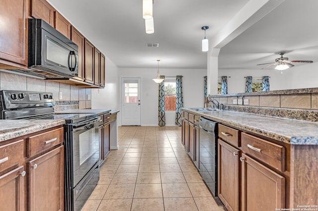 kitchen with sink, black appliances, decorative light fixtures, light tile patterned floors, and tasteful backsplash