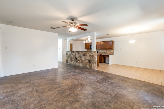 unfurnished living room with dark tile patterned floors and ceiling fan