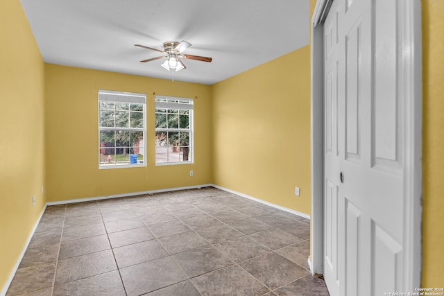 tiled spare room with ceiling fan