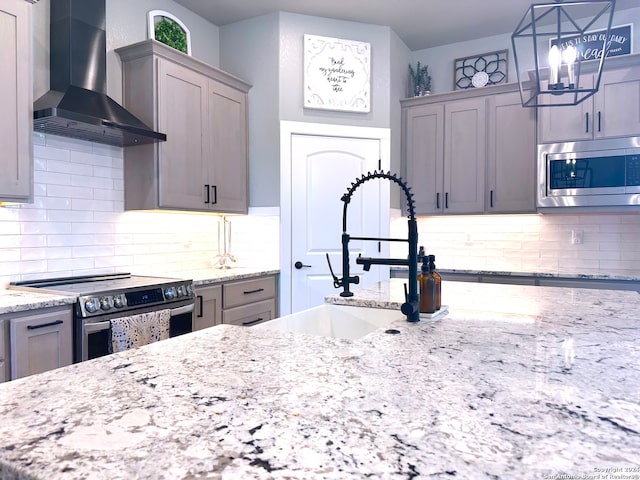 kitchen featuring gray cabinets, wall chimney exhaust hood, pendant lighting, and appliances with stainless steel finishes