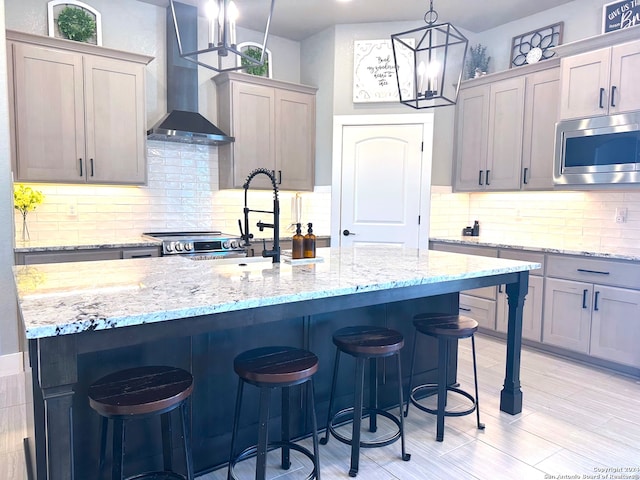 kitchen with a kitchen island with sink, stainless steel microwave, and wall chimney range hood