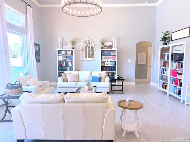 living room with light hardwood / wood-style floors, crown molding, a high ceiling, and a chandelier