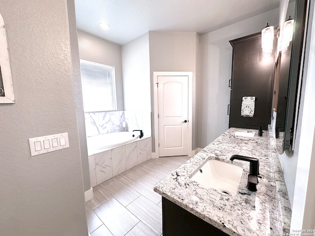 bathroom featuring tiled bath and vanity