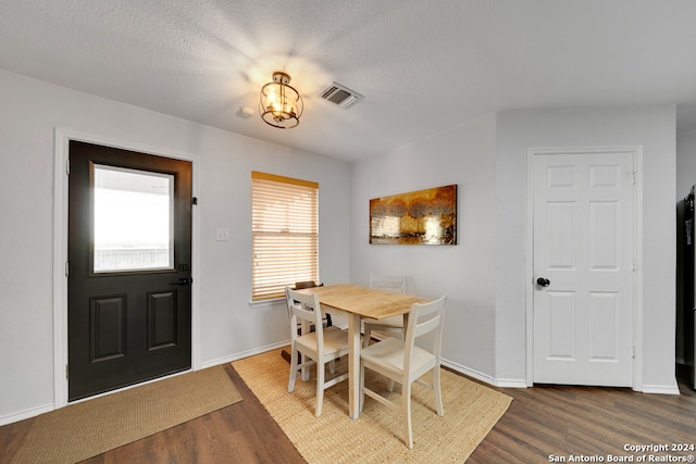 dining room with a notable chandelier, a textured ceiling, and dark hardwood / wood-style flooring