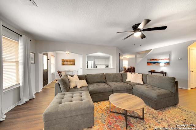 living room with a textured ceiling, wood-type flooring, and ceiling fan