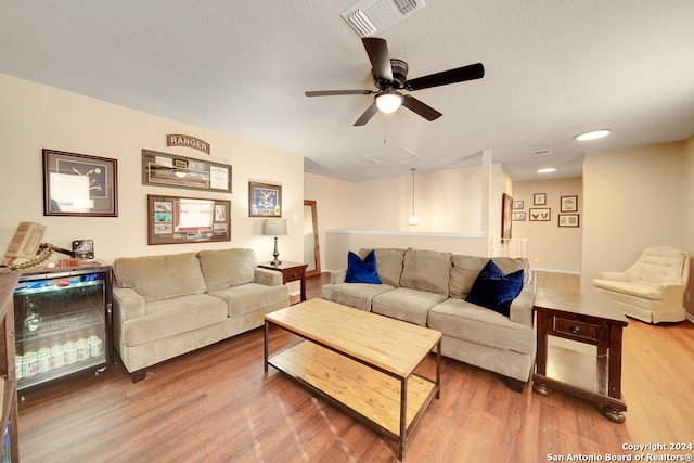 living room with ceiling fan, wood-type flooring, and a textured ceiling