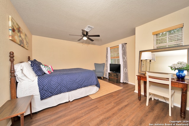 bedroom with ceiling fan, a textured ceiling, multiple windows, and dark hardwood / wood-style floors