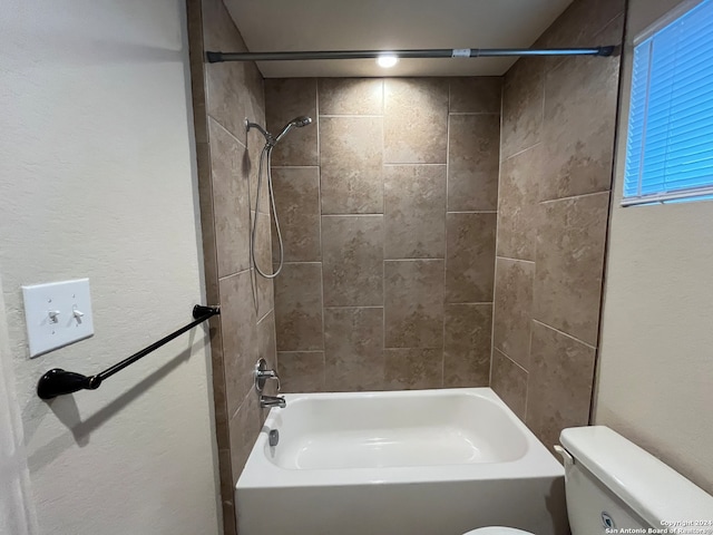 bathroom featuring toilet and tiled shower / bath combo