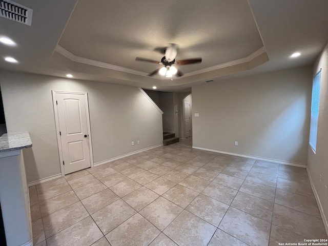 empty room featuring ceiling fan, a raised ceiling, and ornamental molding