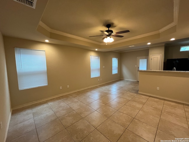 spare room with crown molding, a raised ceiling, light tile patterned floors, and ceiling fan