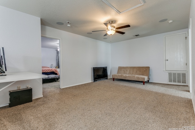 living area with a textured ceiling, carpet flooring, and ceiling fan