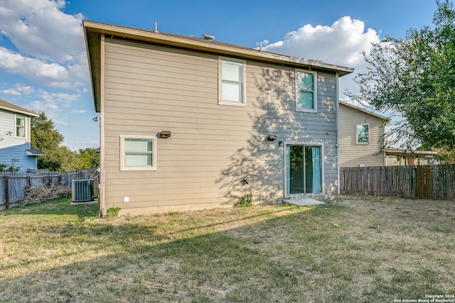 rear view of property featuring a yard and central AC unit