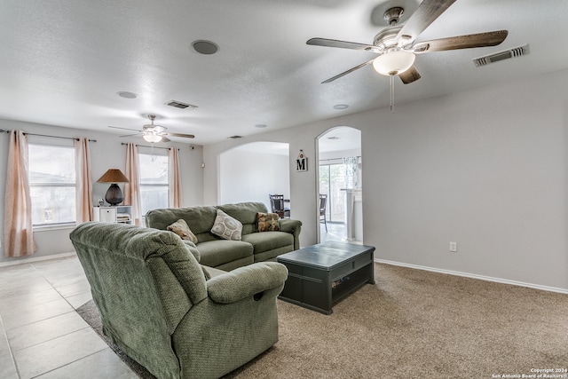 tiled living room with a textured ceiling and ceiling fan