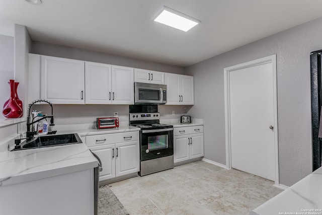 kitchen featuring light stone countertops, sink, appliances with stainless steel finishes, and white cabinets