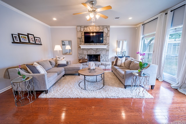 living room with hardwood / wood-style flooring, ceiling fan, crown molding, and a fireplace