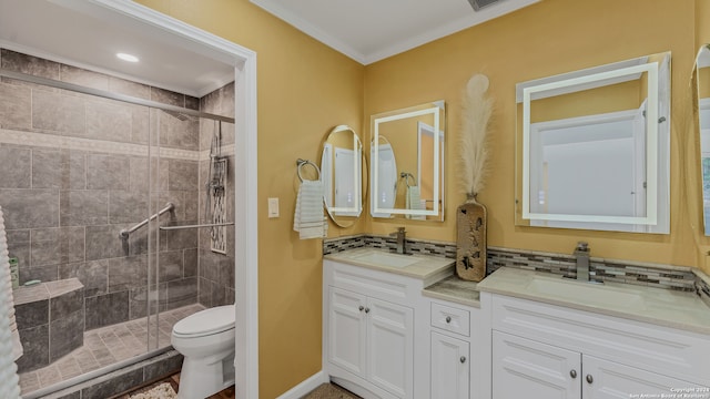 bathroom featuring vanity, toilet, ornamental molding, and a shower with shower door