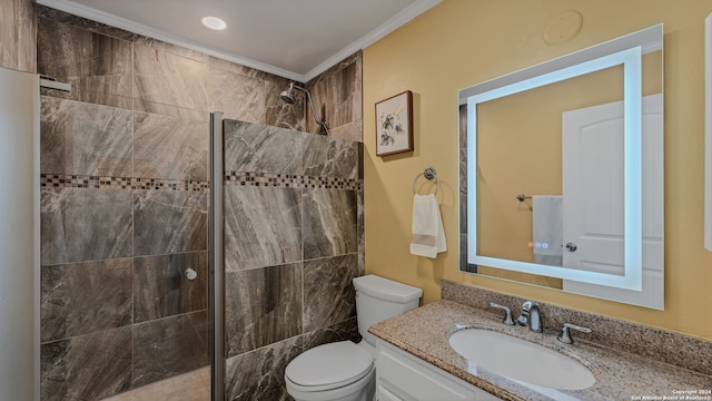 bathroom with toilet, ornamental molding, vanity, and a tile shower