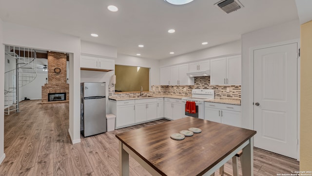 kitchen featuring white electric range, light wood-type flooring, white cabinetry, and stainless steel refrigerator