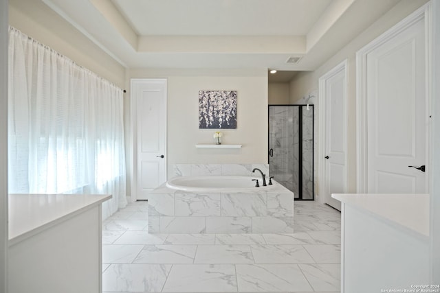 bathroom featuring vanity, separate shower and tub, and a tray ceiling