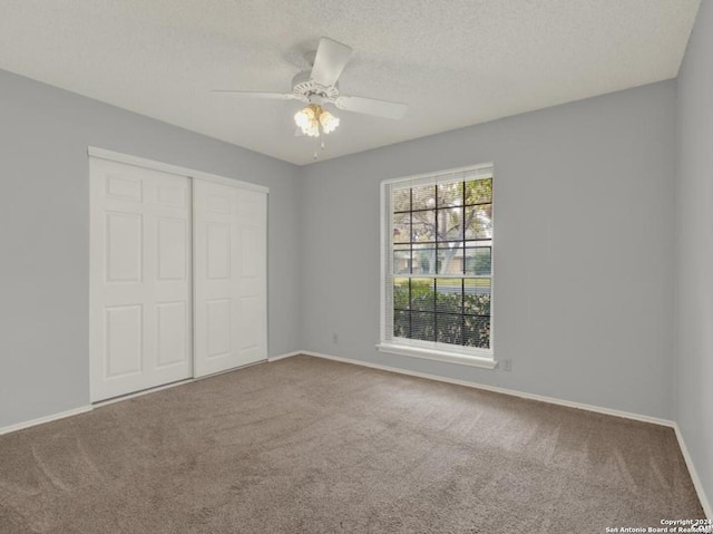 unfurnished bedroom with a closet, ceiling fan, carpet, and a textured ceiling