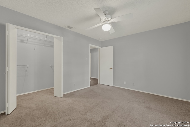 unfurnished bedroom with a closet, carpet floors, a textured ceiling, and ceiling fan