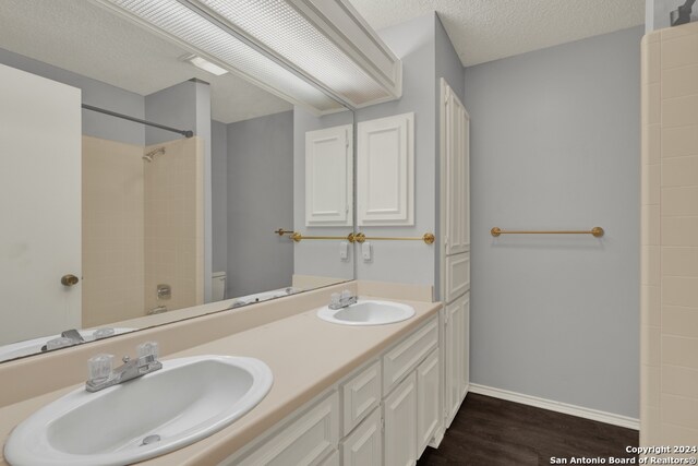 full bathroom with toilet, bathtub / shower combination, hardwood / wood-style floors, vanity, and a textured ceiling