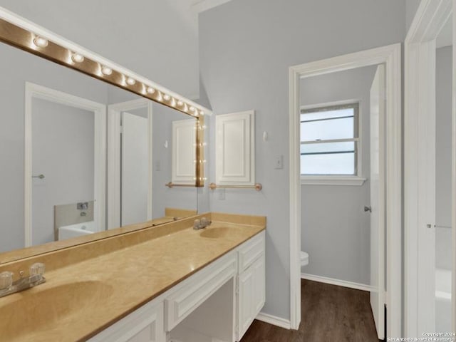 bathroom featuring vanity, toilet, wood-type flooring, and a bath