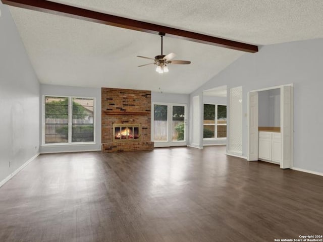 unfurnished living room featuring ceiling fan, a healthy amount of sunlight, beamed ceiling, and dark hardwood / wood-style flooring