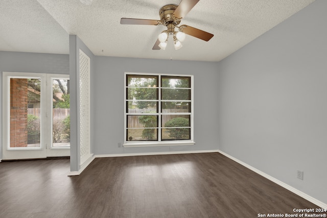 empty room with a wealth of natural light, a textured ceiling, dark hardwood / wood-style floors, and ceiling fan