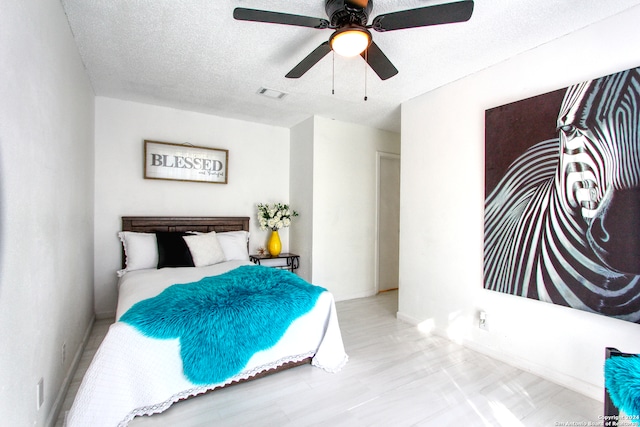 bedroom featuring light hardwood / wood-style flooring, a textured ceiling, and ceiling fan