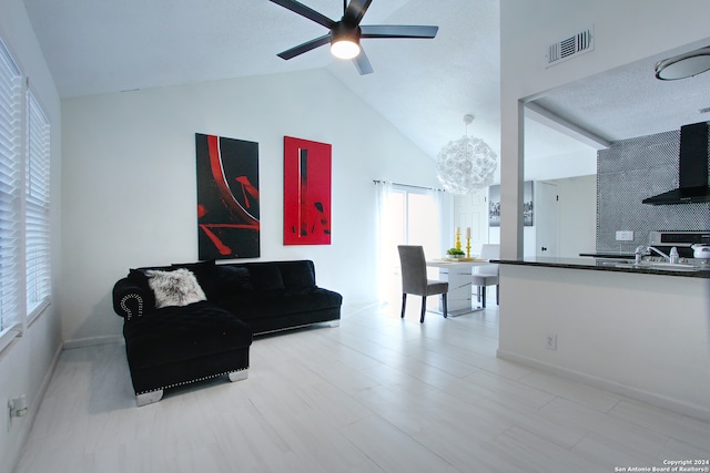 living room featuring a textured ceiling, sink, high vaulted ceiling, and ceiling fan